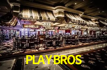 Escena dinámica inspirada en casino con iluminación PLAYBROS, cartas, fichas e íconos de juegos digitales en un espacio moderno de juegos.